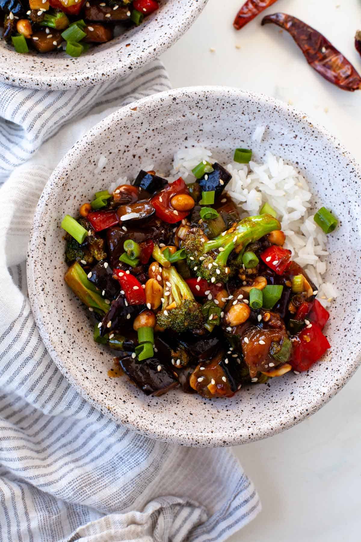 kung pao vegetables with rice in white speckled bowls, dried chilis, towel
